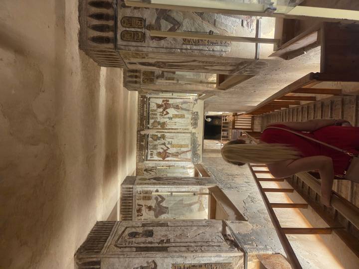 Intérieur d'un tombeau égyptien antique avec des hiéroglyphes et une personne admirant les murs.