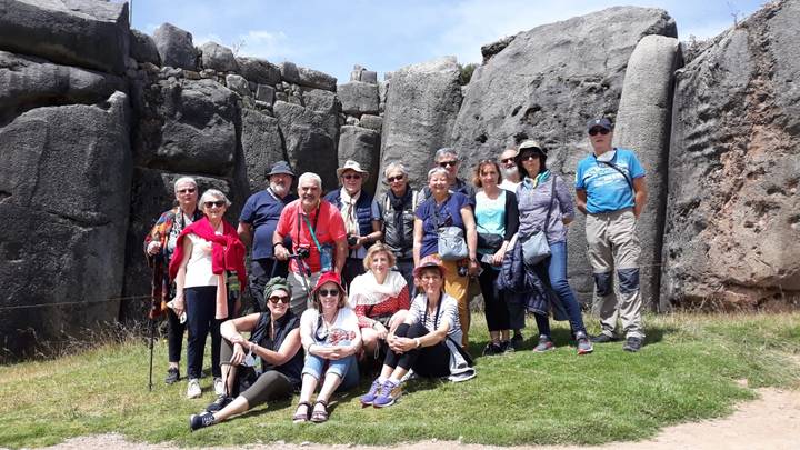 Group of tourists posing in front of ancient stone ruins