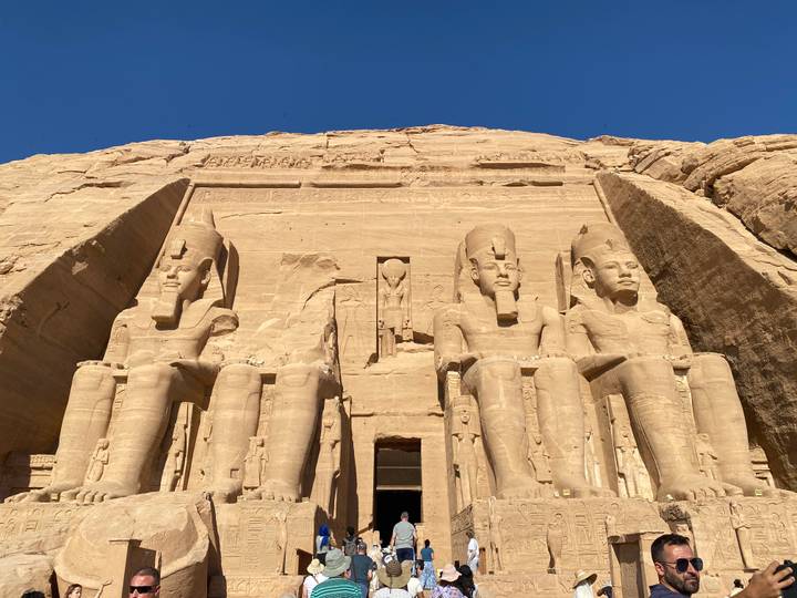 Des statues colossales de pharaons sculptées dans une façade rocheuse.