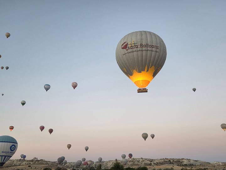 Des montgolfières flottant dans le ciel avec un ballon ayant du texte visible.