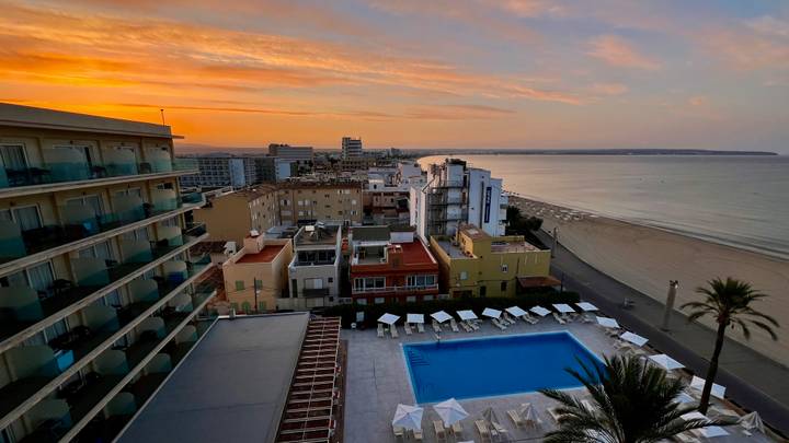 Zone urbaine avec une plage et une piscine au coucher du soleil.