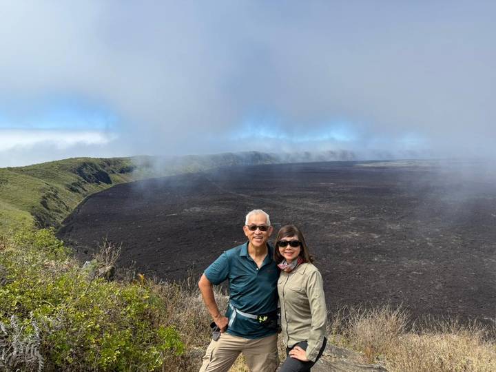 Couple posant devant un paysage volcanique.