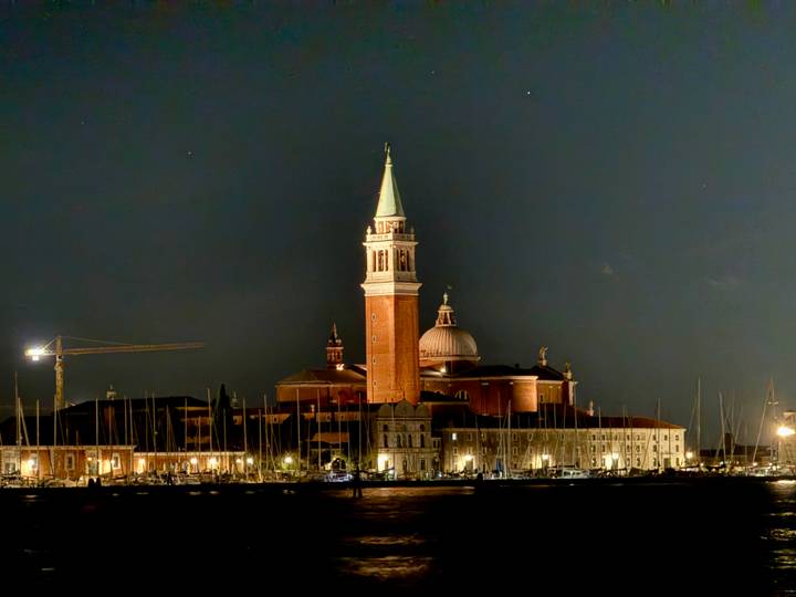 Vue nocturne d'une église éclairée avec un haut clocher à Venise.