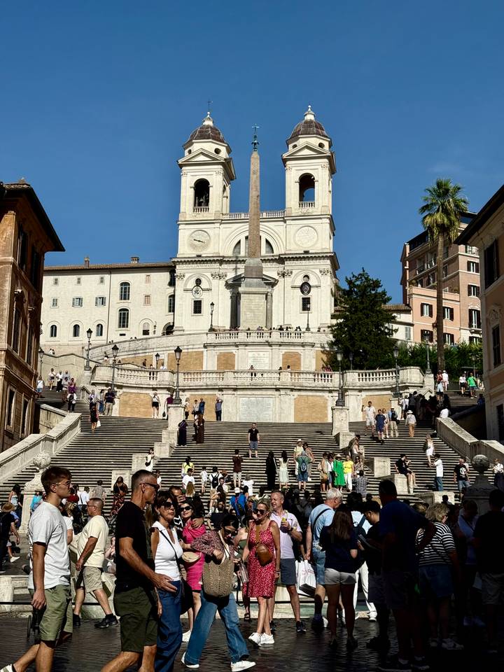 Foule aux escaliers de la Trinité-des-Monts à Rome, sous un ciel dégagé.