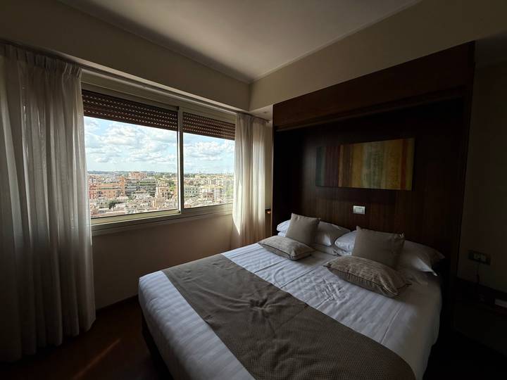 Une chambre d'hôtel avec un lit double et une vue par la fenêtre sur l'horizon de la ville.