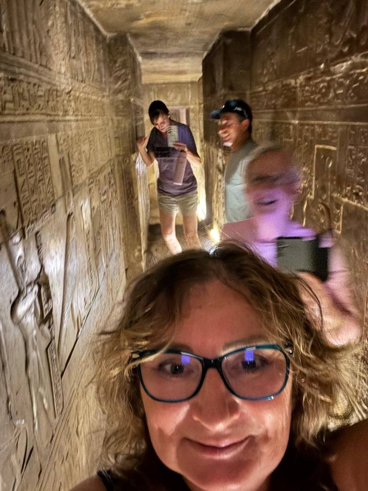 Des gens à l'intérieur d'un passage antique étroit avec des hiéroglyphes.