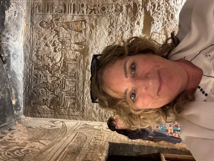 Personne prenant un selfie devant des sculptures murales anciennes.