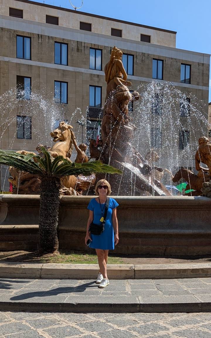 Femme debout devant une fontaine avec des statues