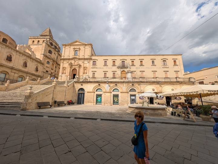 Bâtiment historique avec escaliers et arcades sur une place de ville