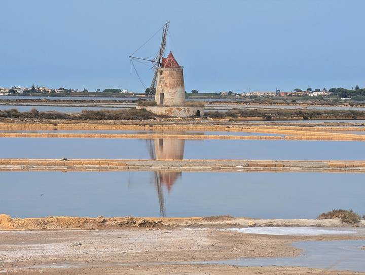 Moulin à vent à côté de marais salants réfléchissants
