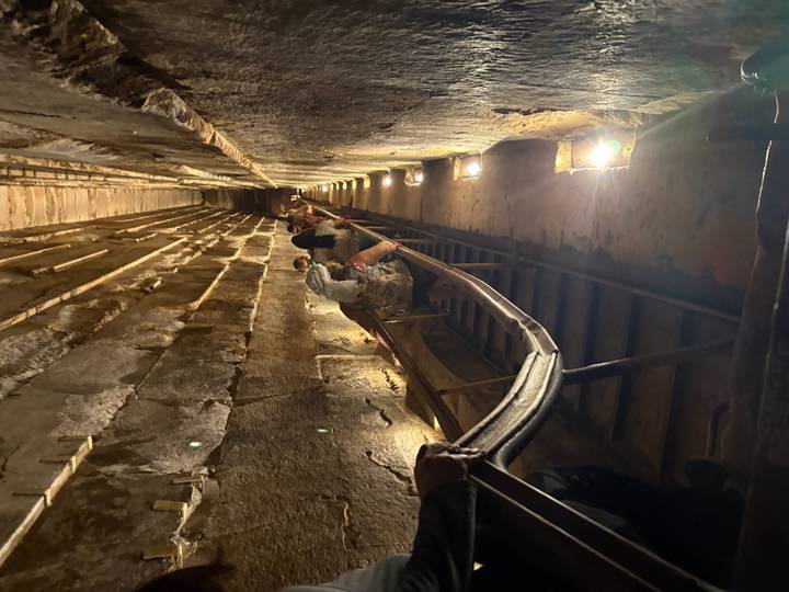 Tourists walking down a staircase inside an ancient pyramid.