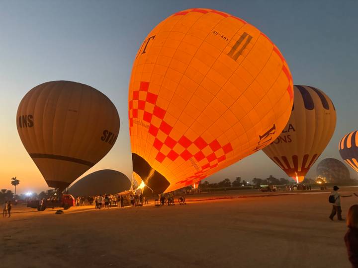 Hot air balloons in various stages of inflation at sunrise.