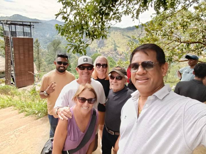 Groupe de personnes souriantes prenant un selfie dans une région montagneuse pittoresque.