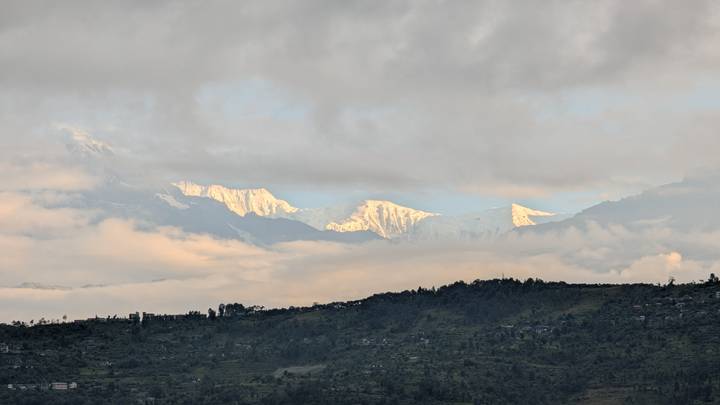 Montagnes enneigées vues de loin à travers les nuages.