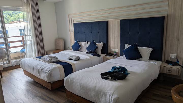 Chambre d'hôtel avec deux lits et vue sur balcon.