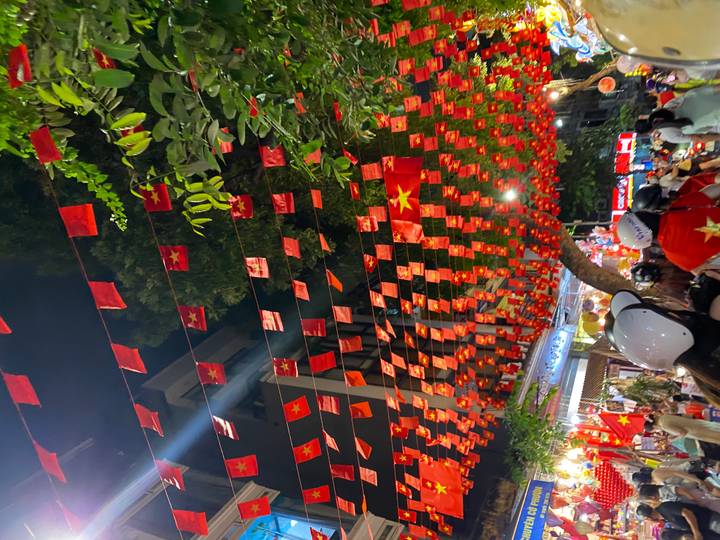Une rue décorée de façon festive avec des drapeaux la nuit à Hanoï, Vietnam.