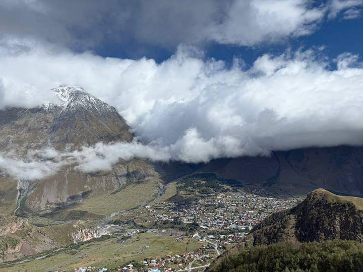 Un village niché dans les montagnes avec un ciel nuageux au-dessus.