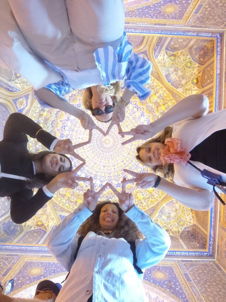 Groupe faisant des signes de paix sous un plafond décoratif.