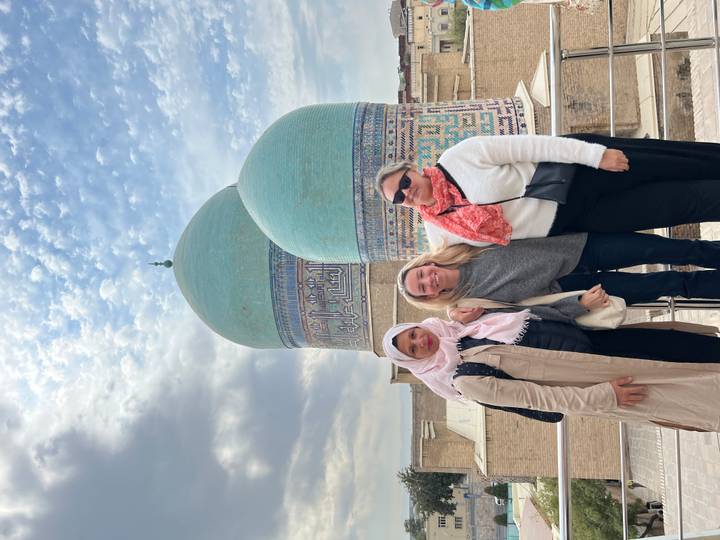 Trois femmes posant devant une mosquée aux dômes bleus.