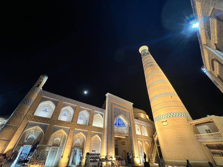 Vue nocturne de bâtiments anciens magnifiquement éclairés avec un croissant de lune.