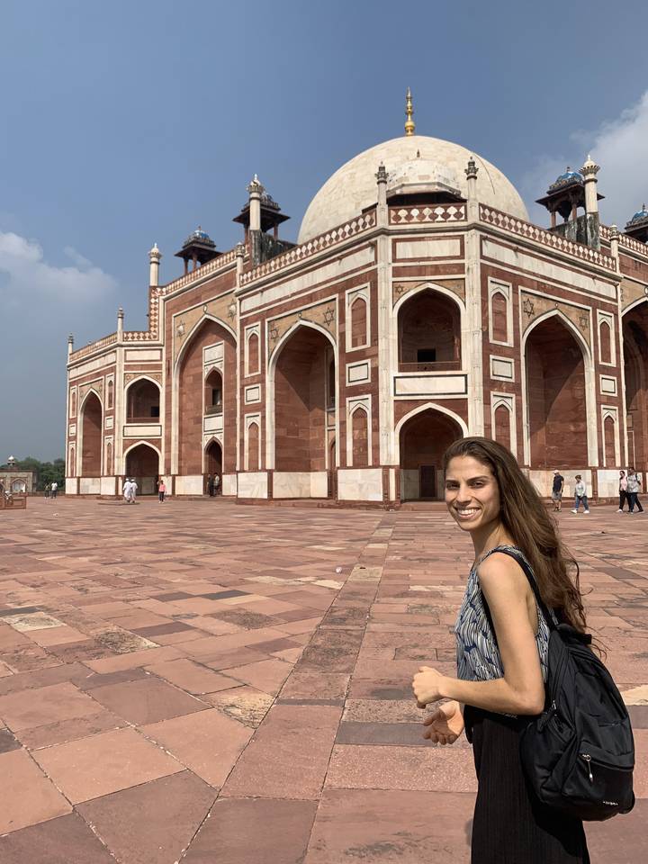 Une femme souriante devant un bâtiment historique.