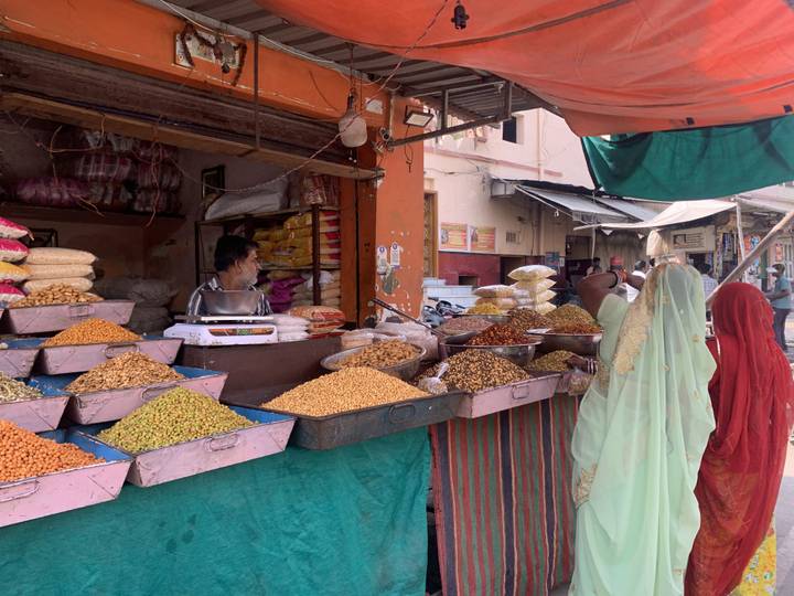 Deux femmes achetant des épices à un étal de marché.