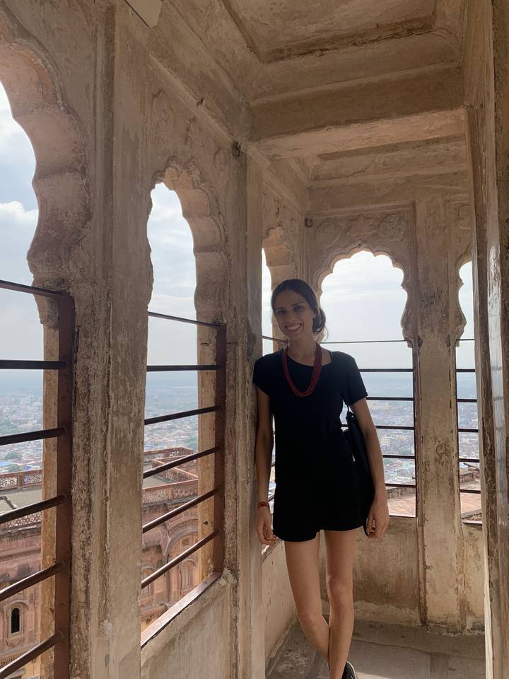 Une femme souriante debout dans une tour avec vue sur la ville.