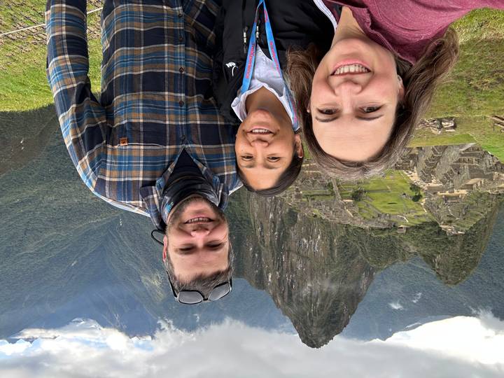 Three people smiling with Machu Picchu in the background.