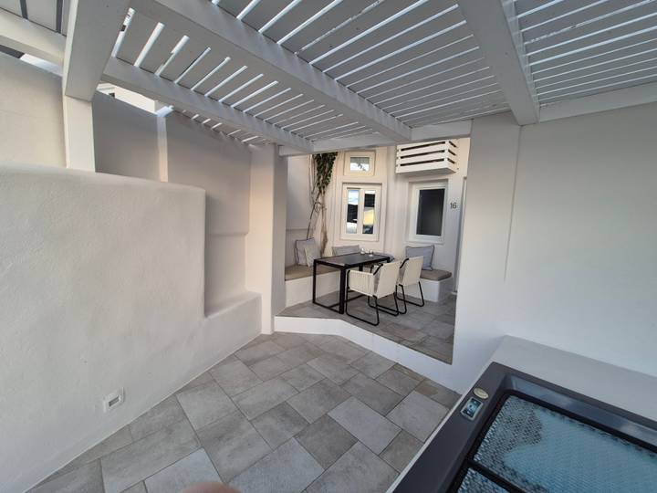 Espace de restauration extérieur avec décor moderne et plantes, couvert par une pergola légère.