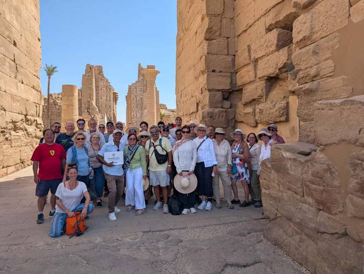 Grand groupe de touristes posant devant des ruines antiques.