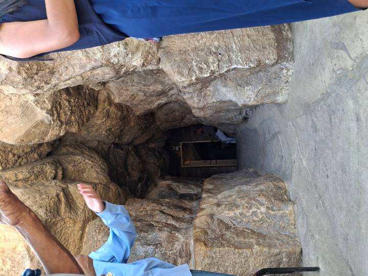 Entrée d'une grotte ou d'un tombeau avec des touristes autour.