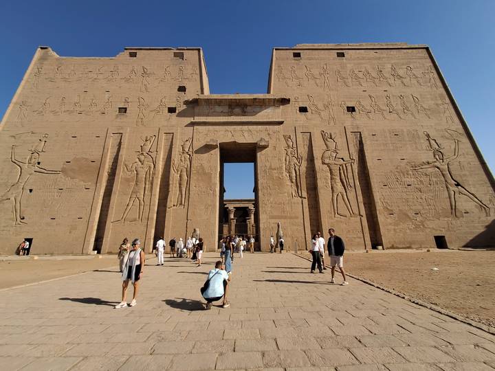 Temple avec de grandes sculptures en pierre et des touristes qui se promènent.