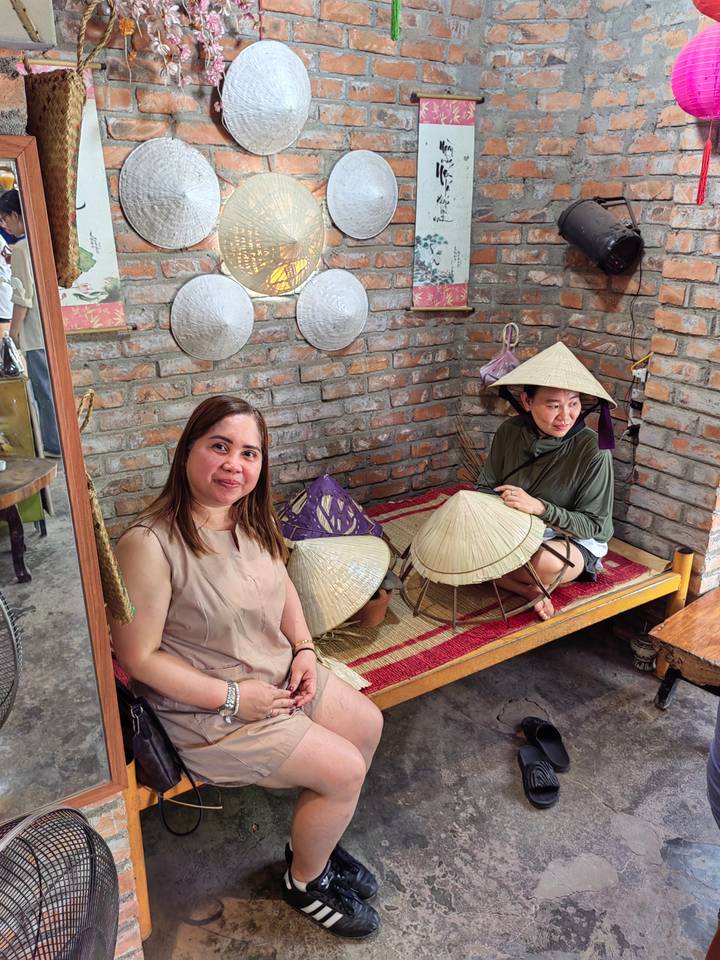 Deux femmes assises avec des chapeaux traditionnels exposés dans une pièce en briques.