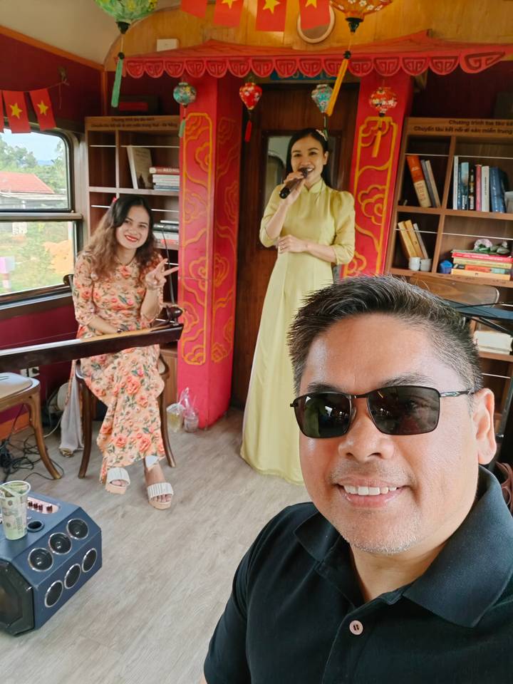 Trois personnes en tenue traditionnelle dans une pièce chaleureusement décorée.