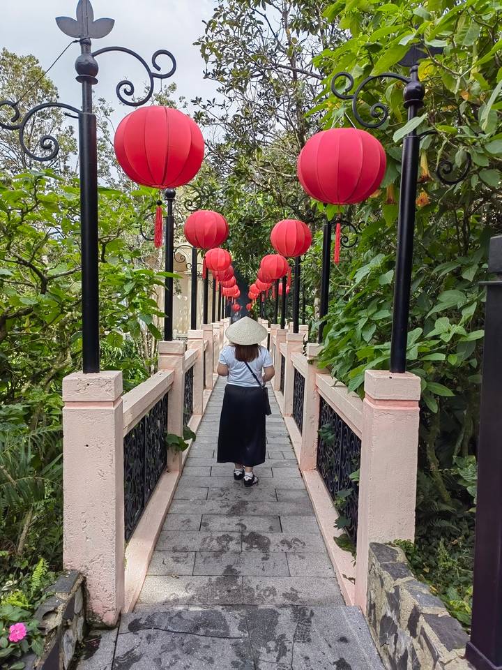 Une personne qui s'éloigne sur un chemin décoré de lanternes rouges.
