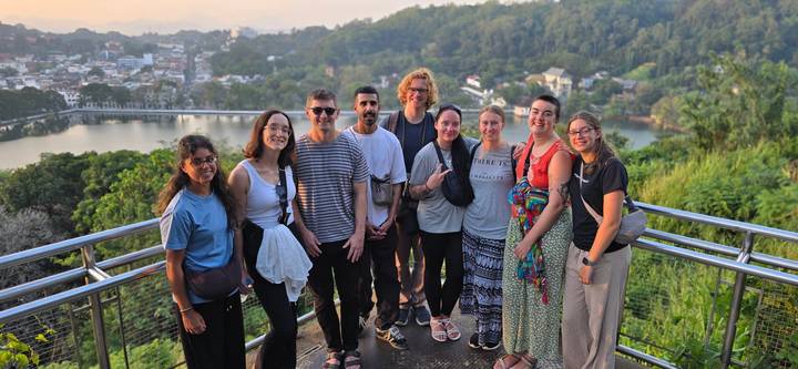 Groupe de personnes posant à un belvédère pittoresque avec des arbres et une rivière.