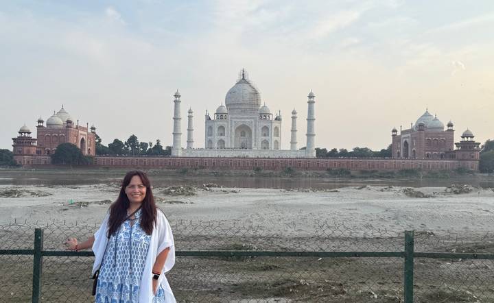 Femme posant près du Taj Mahal depuis l'autre côté de la rivière.