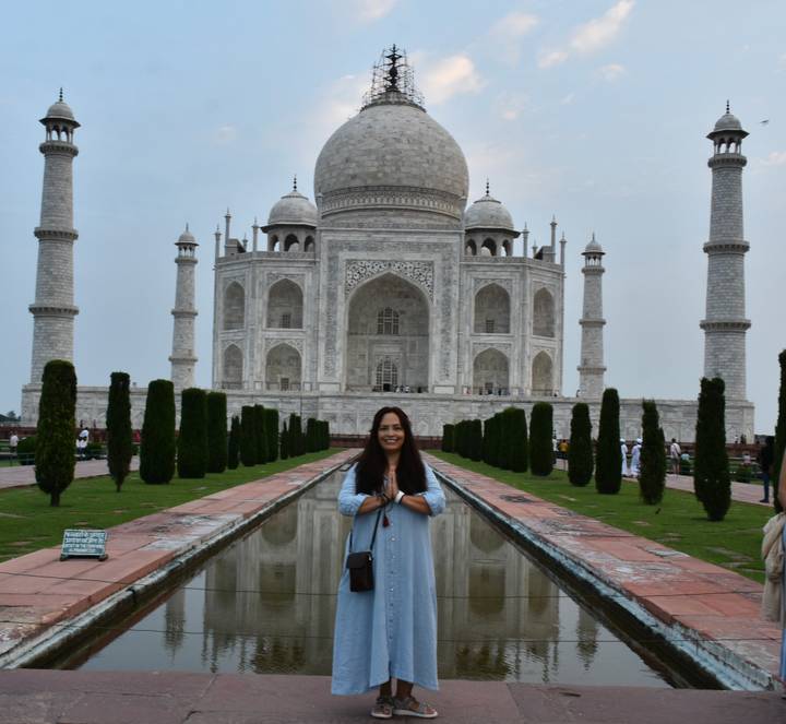Femme debout devant les jardins du Taj Mahal.