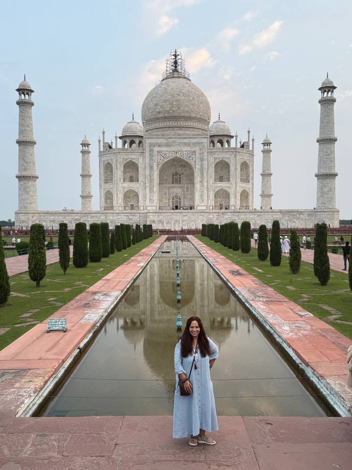 Femme posant avec le Taj Mahal dans le reflet.