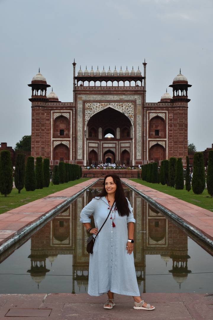 Femme posant avec la porte du Taj Mahal visible.