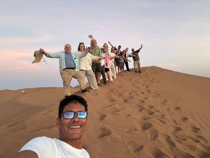 Groupe de personnes posant au sommet d'une dune de sable.