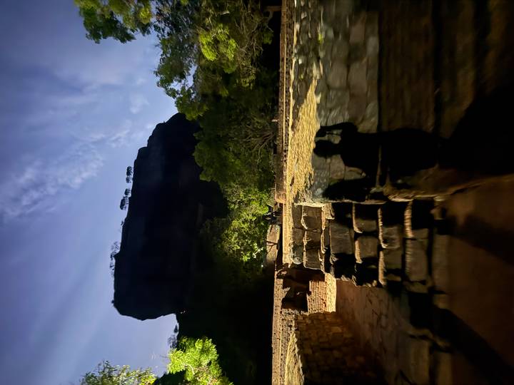 Vue en silhouette d'une forteresse rocheuse la nuit avec des personnes.