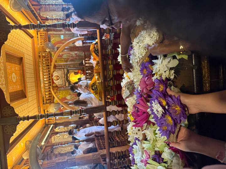 Intérieur bondé d'un temple avec des offrandes et des gens.
