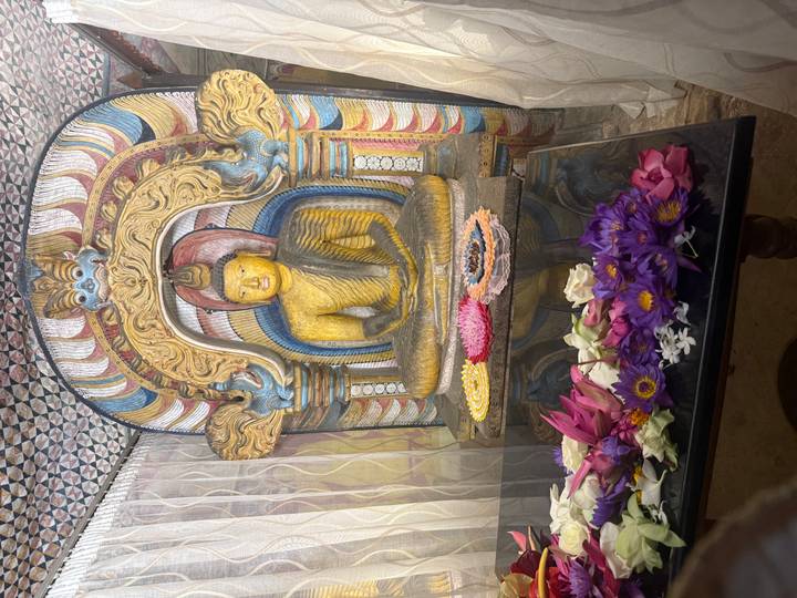 Statue de Bouddha avec des offrandes florales à l'intérieur d'un temple.