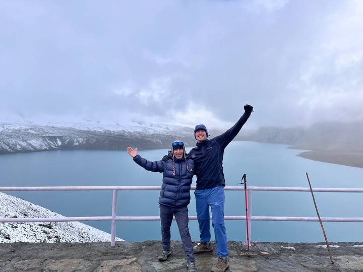 Two hikers celebrating on a viewpoint with a scenic lake and mountains.