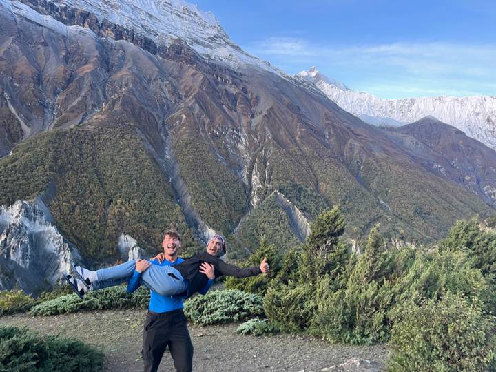 Two people posing playfully with dramatic mountains in the background.