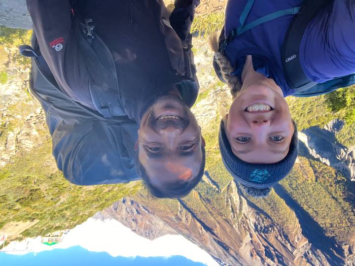 Close-up of two people with hiking gear and mountains behind them.