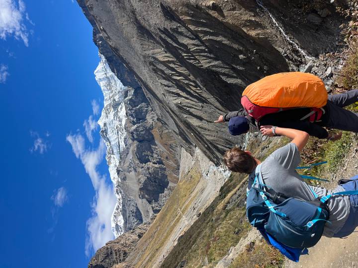 Two people pointing towards a magnificent mountain range with snow caps.