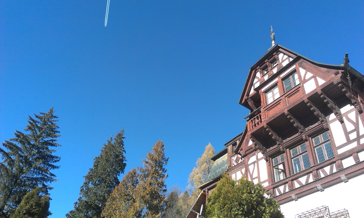 Bâtiment européen entouré d'arbres sous un ciel bleu.