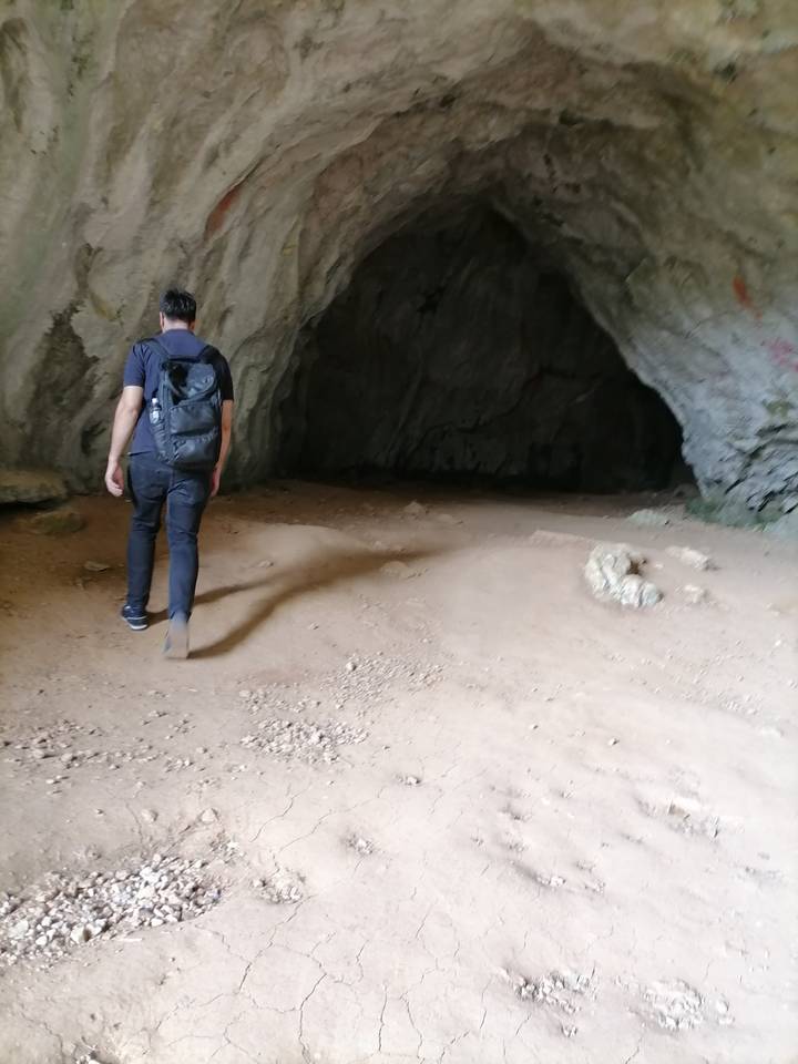 Persona caminando hacia una cueva rocosa.